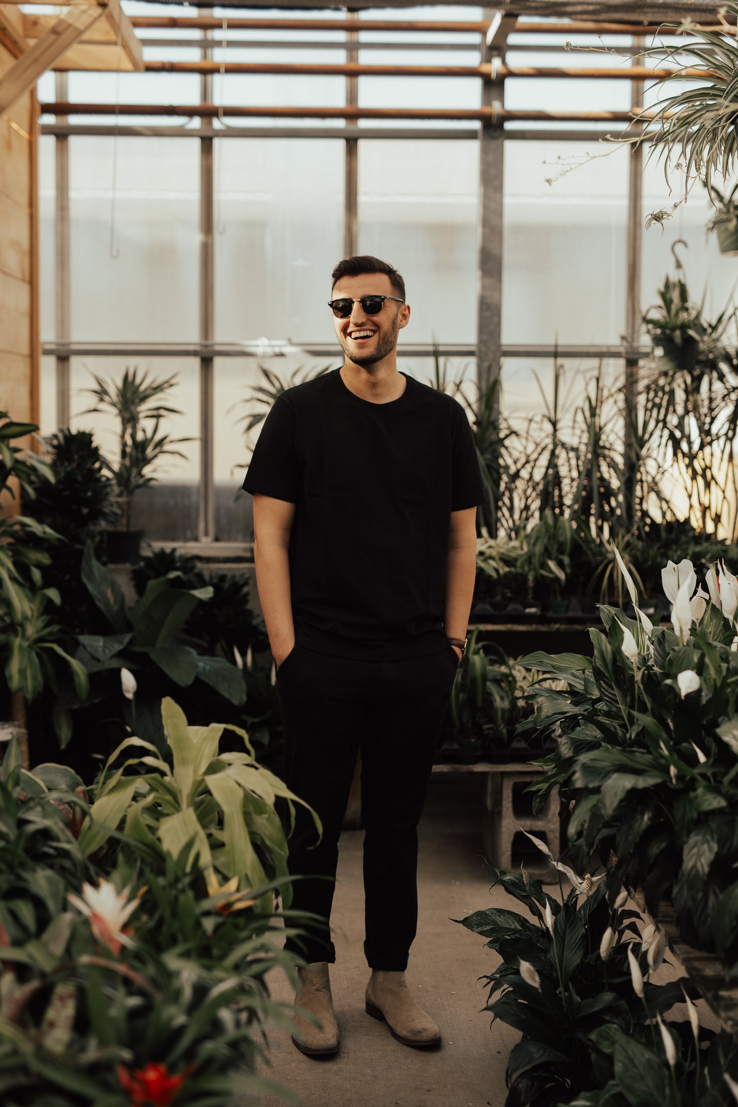 Smiling man wearing sunglasses inside a greenhouse