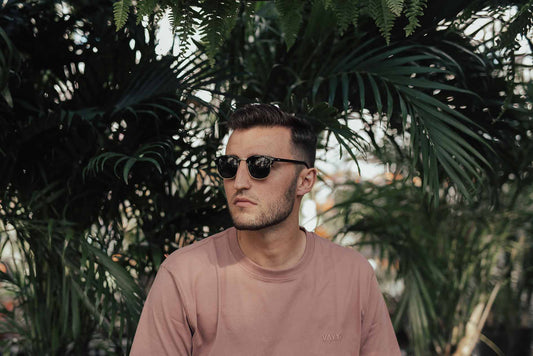 Man wearing sunglasses in a t-shirt while looking contemplative